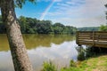 A stunning shot of the vast still silky brown water of the Chattahoochee river with a long wooden boardwalk along the river