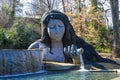 A stunning shot of the waterfall goddess surrounded by lush green trees and plants, bare winter trees with pond and blue sky