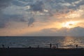 Stunning silhouette of the people on the sandy Echo beach enjoying sunset. Back view of figures of people on the coastline. Sun go