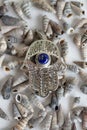 Silver Hamsa Hand with Blue Evil Eye on White Seashells Background