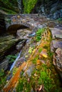 Stunning stone walkway bridge over waterfall gorge with moss and lichen wall