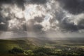 Stunning Summer landscape image of escarpment with dramatic storm clouds and sun beams streaming down