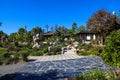 A stunning summer landscape in a Japanese garden with lush green trees and plants with brown buildings and clear blue sky Royalty Free Stock Photo