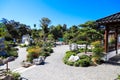 A stunning summer landscape in a Japanese garden with lush green trees and plants with brown buildings and clear blue sky Royalty Free Stock Photo