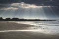 Stunning sun rays bursting from sky over empty yellow sand beach