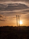 Stunning sun set over field and metal wooden poles electricity t Royalty Free Stock Photo