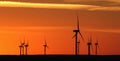 Stunning sunrise illuminates a landscape featuring a line of windmills near a coastal area