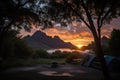 stunning sunrise over a campsite with the silhouette of trees and mountains in the background Royalty Free Stock Photo