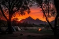 stunning sunrise over a campsite with the silhouette of trees and mountains in the background Royalty Free Stock Photo