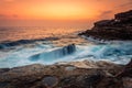 Stunning sunrise and waves crash over rocks on the Sydney sea coast