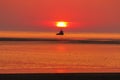 A stunning sunset at the beach image - A boat approaches the falling sun as a couple gaze on