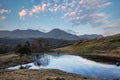 Stunning sunset landscape image of Kelly Hall Tarn in Lake District with Old Man of Coniston in background Royalty Free Stock Photo