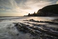Stunning sunset landscape image of Westcombe Beach in Devon England with jagged rocks on beach and stunning cloud formations