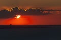 A stunning sunset over the ocean with the sun partially hidden by clouds Royalty Free Stock Photo