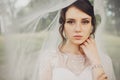 Stunning tender brunette bride stands coverev by her veil