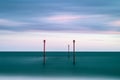 Stunning vibrant conceptual image of posts in sea standing sentinel against the weatherand tide
