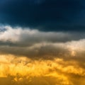 Thunderclouds and yellow-golden fluffy clouds illuminated by rays of sun