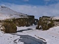 View of the entrance of famous gorge FjaÃÂ°rÃÂ¡rgljÃÂºfur in the south of Iceland with snow-covered rocks, steep cliffs and river.