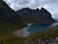 View of Kvalvika Beach with wild surf surrounded by steep mountains and rocky meadows in late summer in Norway.