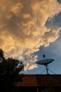 A stunning view of a satellite dish against a dramatic sky filled with golden clouds at sunset Royalty Free Stock Photo