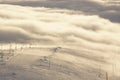 Stunning views of the ski slope and ski lift on the mountain in the middle of the clouds below and in front, sunset Royalty Free Stock Photo