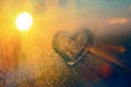 Stunning vintage amber sunrise light with heart love inscription on frozen window glass. Soft focus. Background with copy space