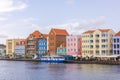 Stunning vista of vibrant houses in the heart of Willemstad, overlooking St. Anna Bay with backdrop of cloudy sky.