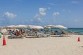 Stunning vista of white sandy beach along Atlantic Ocean with people relaxing on sun loungers beneath umbrellas.