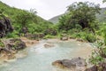 Waterfall in Ayn Khor and Lush green landscape, trees and foggy mountains at tourist resort, Salalah, Oman