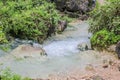 Waterfall in Ayn Khor and Lush green landscape, trees and foggy mountains at tourist resort, Salalah, Oman