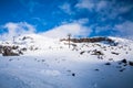 Stunning winter landscape with snow blanketed mountain range and sky lift lines climbing up the slope. Tractor tracks