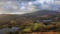 Stunning Winter sunrise landscape view from Loughrigg Fell across Loughrigg Tarn with stunning dappled sunlight Royalty Free Stock Photo