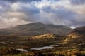 Stunning Winter sunrise landscape view from Loughrigg Fell across Loughrigg Tarn with stunning dappled sunlight Royalty Free Stock Photo