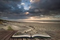 Stunning Winter sunrise over West Wittering beach in Sussex England with wind blowing sand across the beach in pages of open book