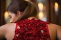 A stunning woman in a red dress adorned with beautiful flowers on her back, women Back massage with red rose petals, AI Generated