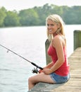 Stunning young blonde woman fishing from pier Royalty Free Stock Photo