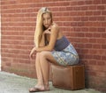 Beautiful blonde woman in strapless sundress with vintage suitcase