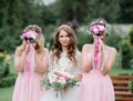 Stunning young bride and bridesmaids in pink dresses stand with wedding bouquets in the park Royalty Free Stock Photo