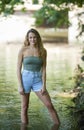 Stunning young brunette woman standing in shallow creek