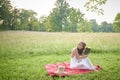 Beautiful young woman in white dress on picnic blanket on summer afternoon
