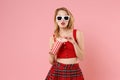 Stunning young woman girl in red sexy clothes, dark sunglasses isolated on pastel pink wall background. People sincere Royalty Free Stock Photo