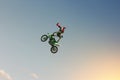 A stunt biker performs a trick in the sky