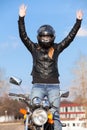 Stunt girl balancing while riding motorcycle without arms, hands up