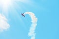 Stunt plane trailing smoke bright sun and clouds Royalty Free Stock Photo