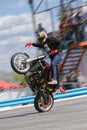 The stuntman shows tricks on a motorcycle while standing on it on one wheel with one foot and driving with one hand