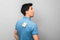 Stupid looking man in blue shirt with a yellow sticky note with word fool on his back stupidly looking up