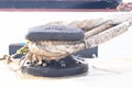 Sturdy metal mooring bollard at pier big lack installed on concrete with a rope attached. Royalty Free Stock Photo