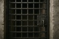 Sturdy prison gate with iron grate and keyhole on solid stone wall. concept of security, confinement, institutional structure Royalty Free Stock Photo