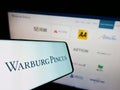 Cellphone with logo of American private equity company Warburg Pincus LLC on screen in front of website.