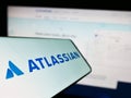 Cellphone with logo of Australian software company Atlassian Corporation on screen in front of business website.